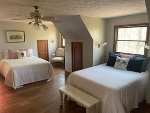 A bedroom with two beds, a ceiling fan, a window, and a wooden floor. - Oak Haven 1827 Cabin Rental (Union Township)
