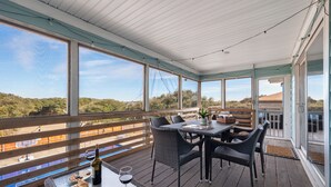 Un patio techado al aire libre con una mesa dispuesta para comer, mostrando croissants y copas de vino.
