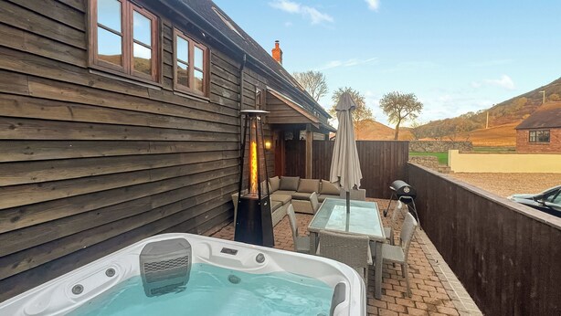Un bain à remous avec une terrasse en bois, des sièges d’extérieur et un foyer.