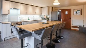 Une cuisine moderne dotée d’un îlot central, de tabourets de bar et d’une table à manger en bois.