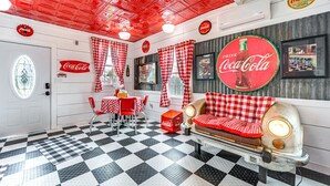Une pièce à l’ambiance rétro, avec un sol à carreaux, des meubles anciens et des éléments de décoration à l’effigie de Coca-Cola.