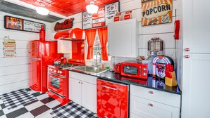 Une cuisine au style rétro, avec des appareils électroménagers rouges, un sol à carreaux et un décor d’époque.