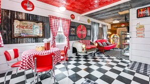 Un restaurant à la décoration rétro, avec un sol à carreaux, des éléments de décoration rouge et blanc, et des objets de collection anciens de la marque Coca-Cola.