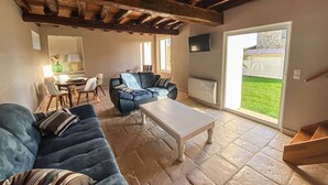 Un salon avec un canapé bleu, une table basse blanche et un téléviseur fixé au mur.