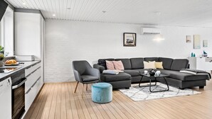 A modern living room with a grey sectional sofa, a round ottoman, and a coffee table.