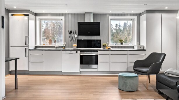 A modern kitchen with white cabinetry, a built-in oven, and a large window.