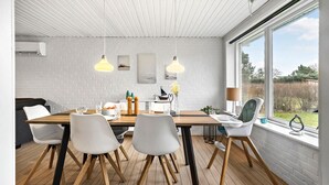 A dining area with a wooden table, white chairs, and pendant lighting.