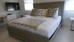 Ein modernes Schlafzimmer mit einem großen Bett, einem flachbildfernseher an der Wand und einem Nachttisch.
