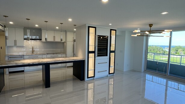 A modern kitchen with a central island, built-in cabinets, and a large window offering a view.