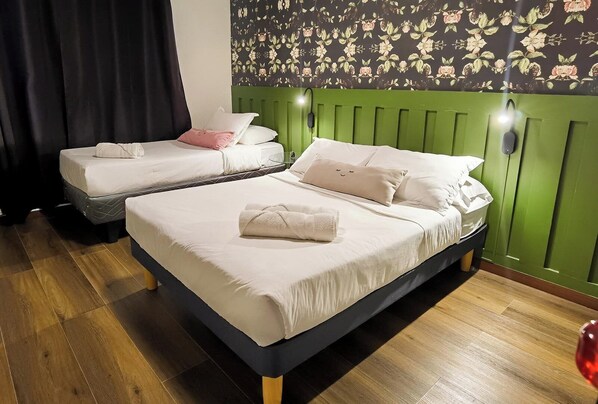 A hotel room with two beds, one with a green headboard and the other with a black headboard.