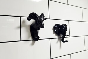 Dos figuras de animales negros montadas en una pared de azulejos blancos.
