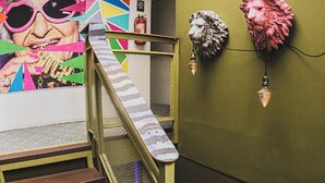 A staircase with metal railings and wooden steps, leading to a room with a green wall and a colorful mural. - Hotel Velero Cavancha (Iquique)