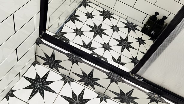 A bathroom with black and white star-patterned tiles and a black bathtub. - Hotel Velero Cavancha (Iquique)