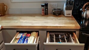 Una cocina con encimeras de madera, dos cajones debajo para guardado, una cafetera, un hervidor y un bloque para cuchillos.