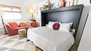 Un dormitorio con cama, sofá, lámpara y ventana.