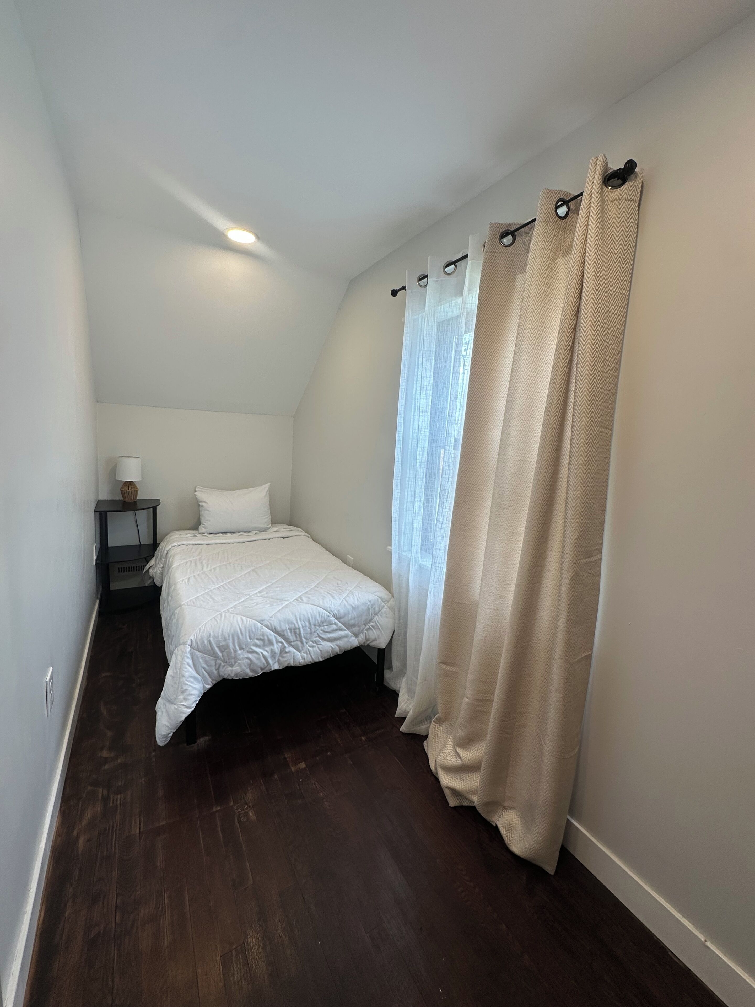 Une chambre à coucher avec un lit, une table de chevet et une lampe.