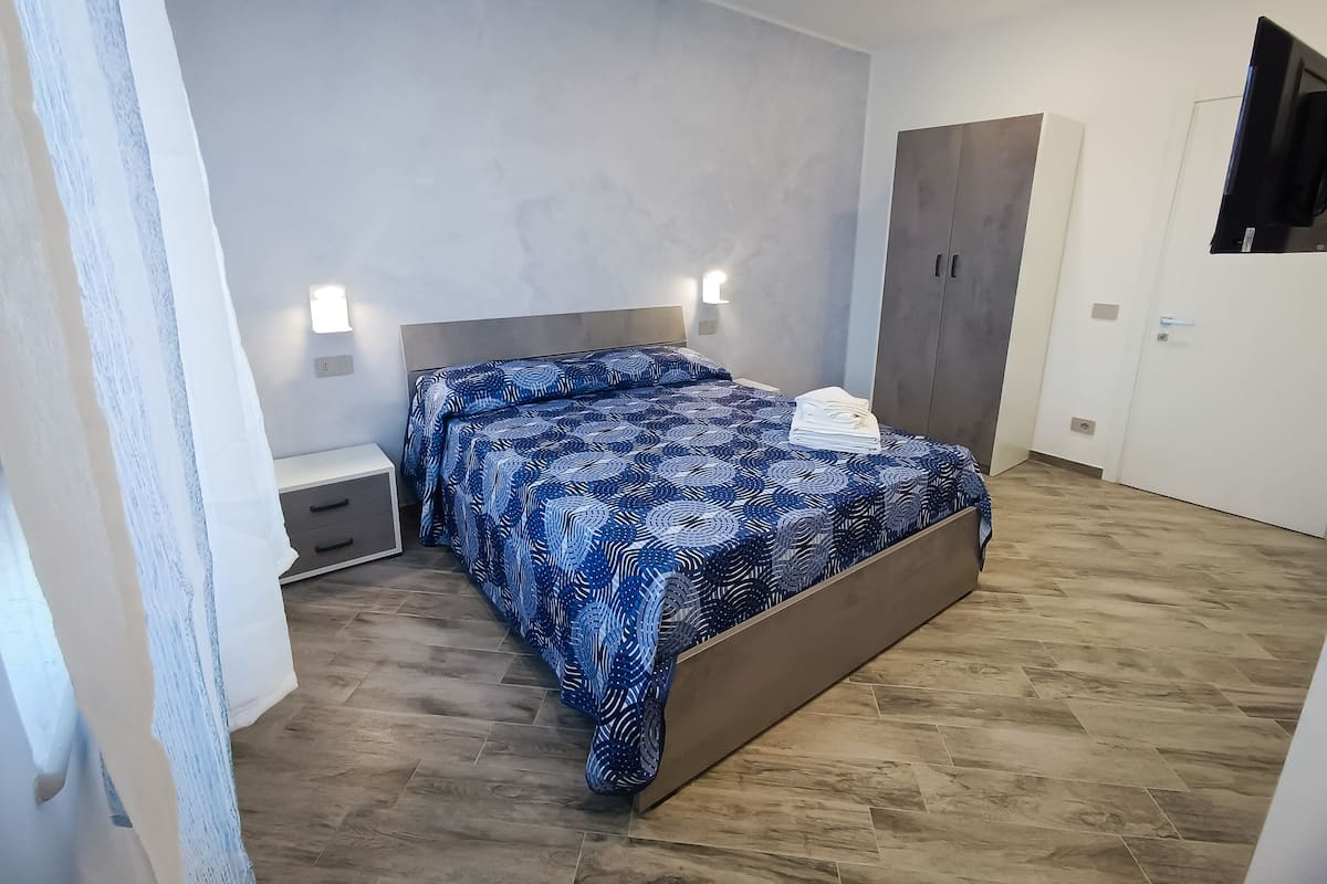 Un dormitorio con cama, mesitas de noche, armario y espejo.