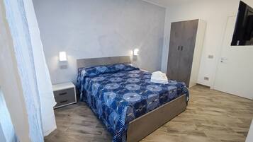 Une chambre à coucher avec un lit, des tables de chevet, une armoire et un miroir.
