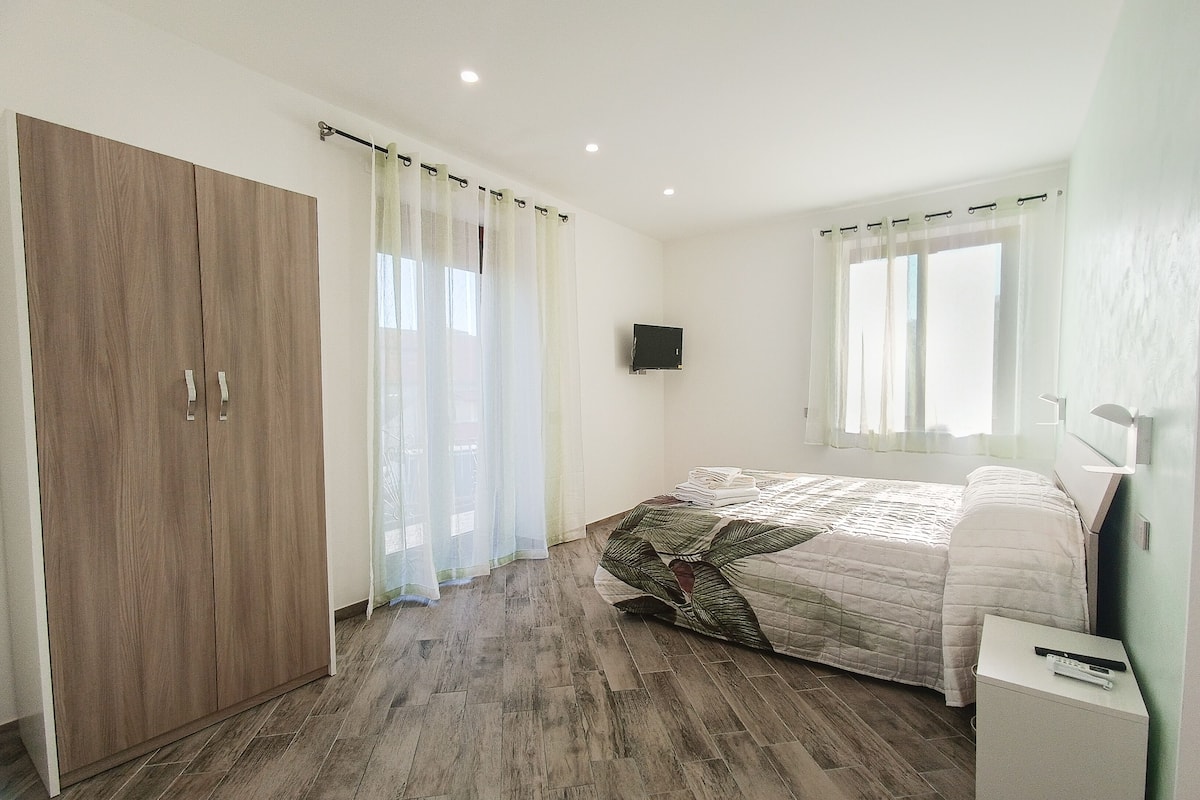 Un dormitorio con cama, armario, televisor y mesita de noche.