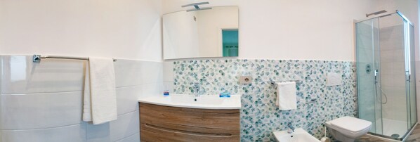 A bathroom with a wooden vanity, a white sink, a mirror, and a glass shower enclosure.