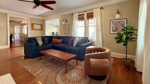Ein Wohnzimmer mit Ecksofa, Couchtisch, Sessel, Stehlampe und einem Blumentopf.