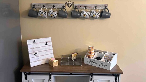 A coffee station with mugs, a coffee bar, and a sign that says "Coffee time".