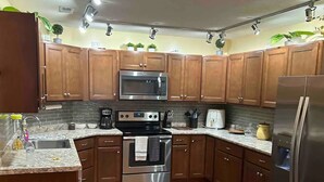 A kitchen with wooden cabinets, stainless steel appliances, a microwave, oven, and a refrigerator.