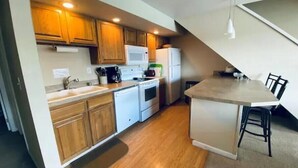 A modern kitchen with wooden cabinets, a microwave, a refrigerator, and a dining area with a table and chairs. - #188 Condo near large pool & shuttle to Gorge Amp-book separately (Quincy)