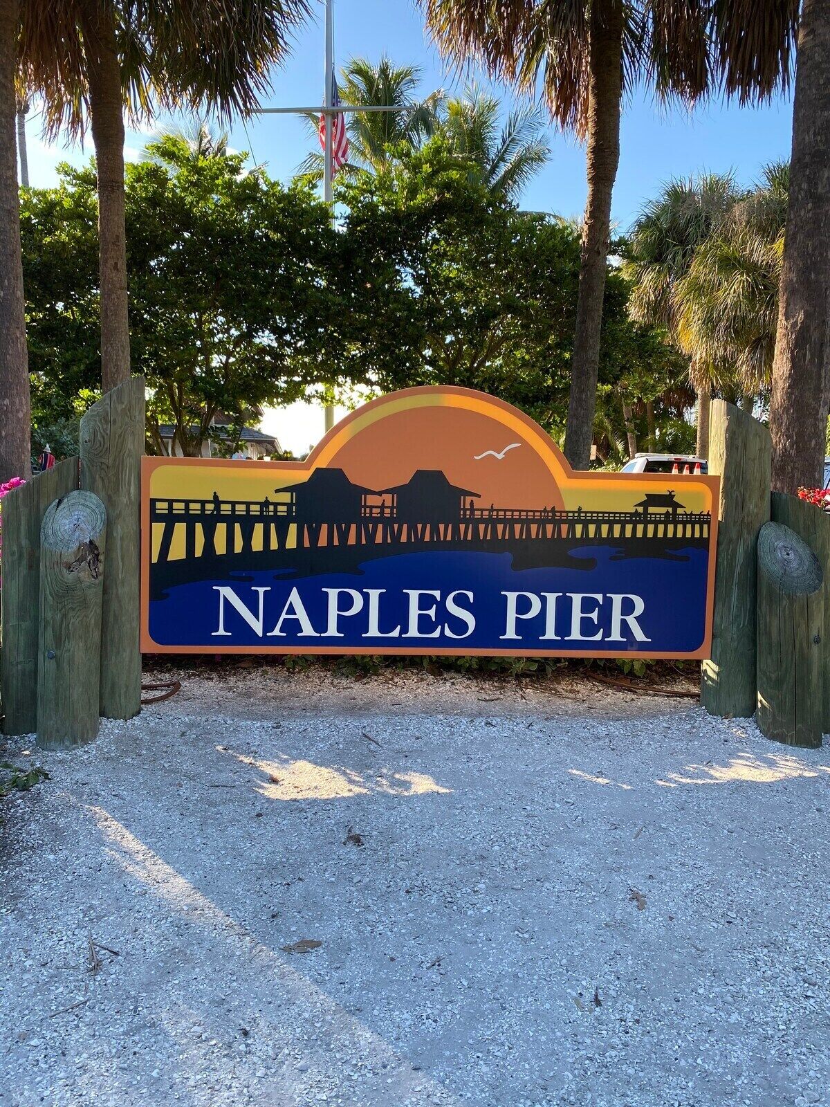 Placa de Naples Pier com silhueta de um pôr do sol e uma gaivota.