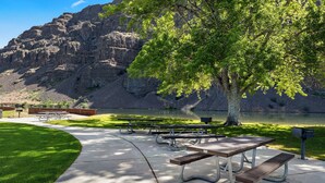 A park with picnic tables, benches, and a lake.