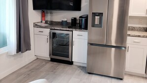 Eine moderne Küche mit Einbauofen, einem Edelstahl-Kühlschrank und einem flachbildfernseher an der Wand.