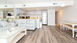 A compact living space with a kitchenette, a dining area, and a seating area with a sofa and a coffee table.