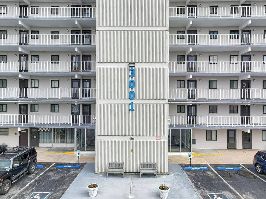 Ein mehrstöckiges Gebäude mit Balkonen, Hausnummer 3001, und ein Parkplatz mit markierten Stellplätzen.
