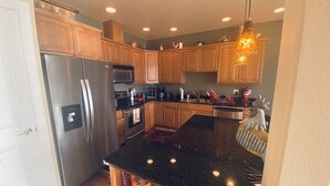 A kitchen with wooden cabinets, stainless steel appliances, a granite countertop, and a hanging light fixture. - A08-Sharp River/Golf Course view near pool/hot tub (Quincy)