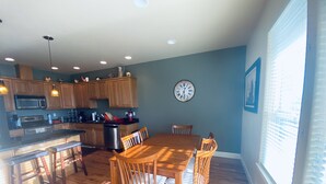 A spacious kitchen with wooden cabinets, a dining table with chairs, and a large wall clock. - A08-Sharp River/Golf Course view near pool/hot tub (Quincy)