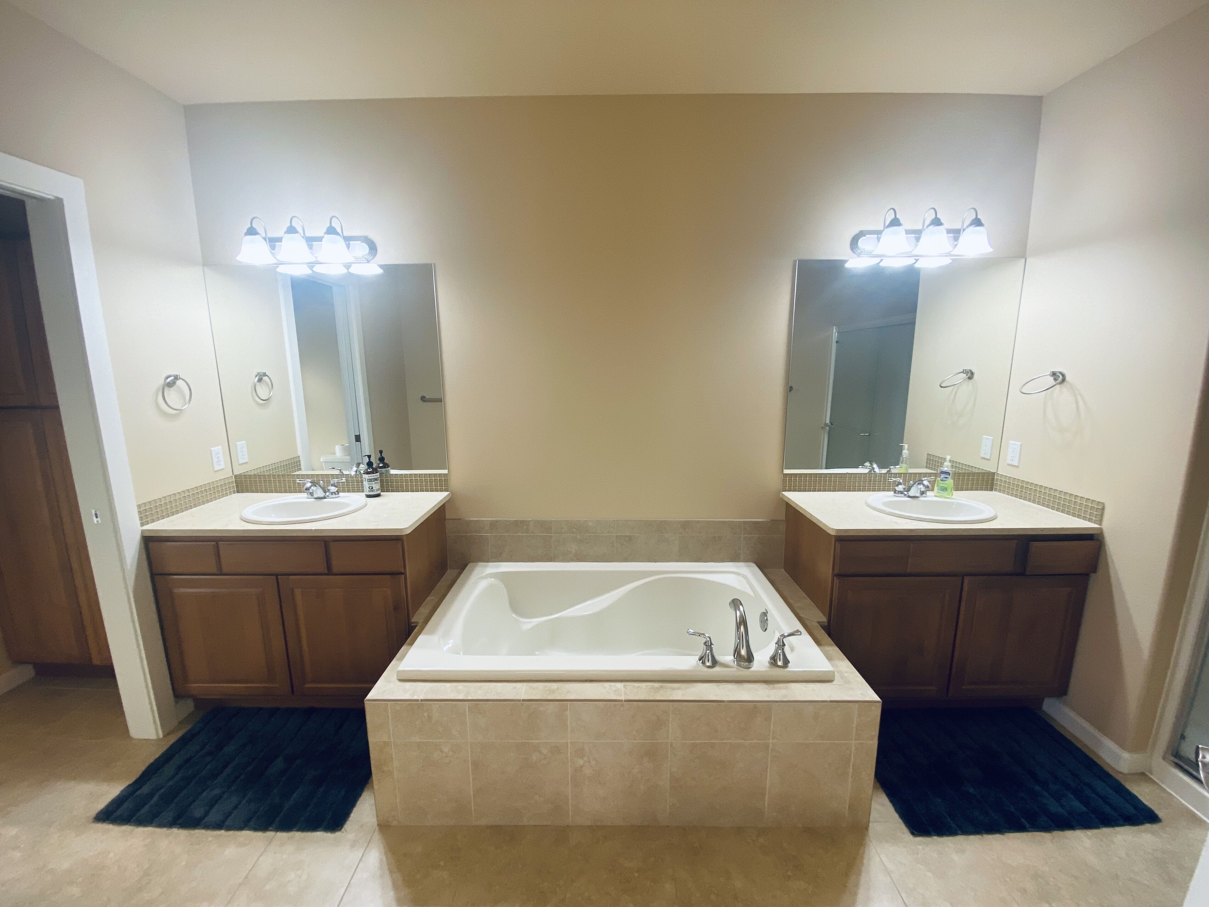Un baño con dos lavamanos, una bañera grande e iluminación en el techo.