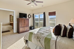 A bedroom with a large bed, a television on a wooden cabinet, a ceiling fan, and a view of a landscape through the window. - B50-Condo near pool & Gorge shuttle (Quincy)