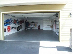 A garage with a concrete floor, a closed garage door, and various stickers on the wall.