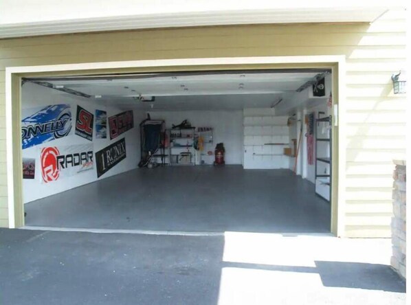 A garage with a concrete floor, a closed garage door, and various stickers on the wall. - B50-Condo near pool & Gorge shuttle (Quincy)
