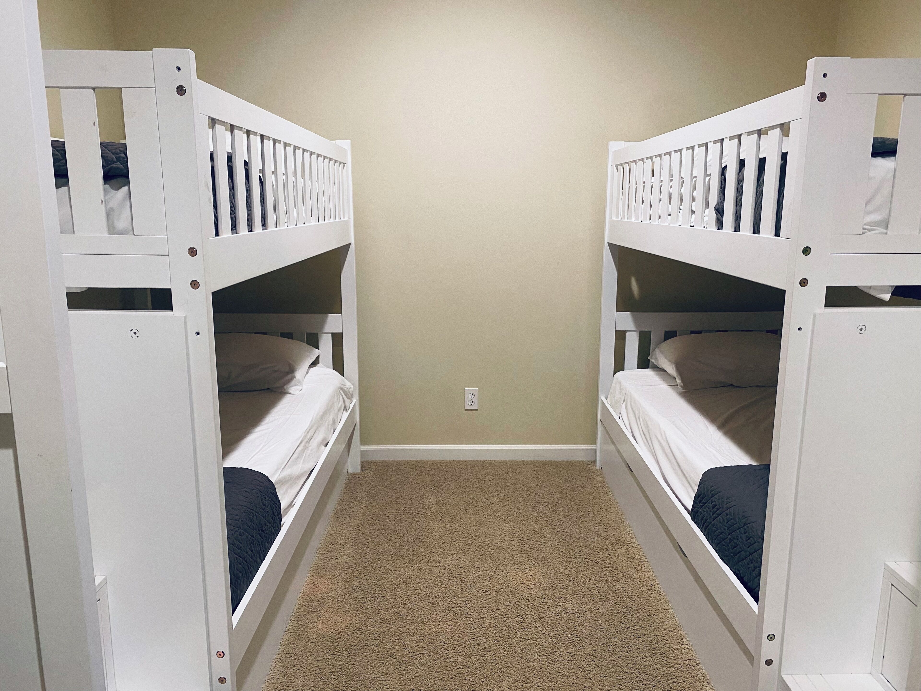 A room with two bunk beds, carpeted floor, and a plain wall.