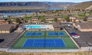 A residential area with a tennis court, a swimming pool, and a parking lot.