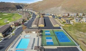 A residential area with houses, a swimming pool, tennis courts, and a parking lot.