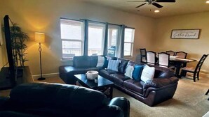 Ein Wohnzimmer mit einer dunkelbraunen Ledersofa, einem Couchtisch und einem Essbereich mit Tisch und Stühlen.