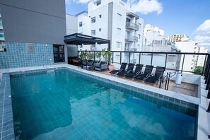 A rooftop pool with clear blue water, surrounded by lounge chairs and a covered seating area. - Studio Sao Paulo PUC Allianz Park 608WB (São Paulo)
