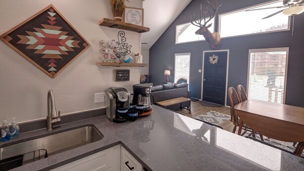 A modern kitchen with a coffee maker, a sink, and a dining area with a table and chairs. - Red River Retreat (Red River)