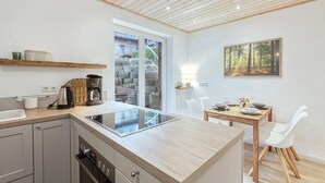 Une cuisine moderne dotée d’un îlot central, d’un plafond en bois et d’un coin repas avec des chaises blanches.