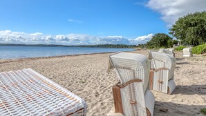 Une plage avec des chaises longues en osier blanc et une rive sablonneuse.