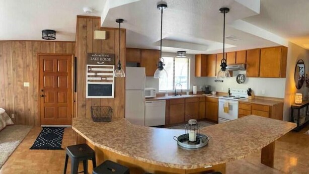 A modern kitchen with a large island, wooden cabinets, and pendant lighting. - Doney Creek Cabin (Lakehead-Lakeshore)
