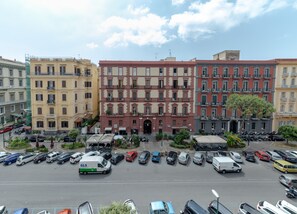 Un edificio a più piani con un ingresso centrale, circondato da auto parcheggiate e un cielo sereno.