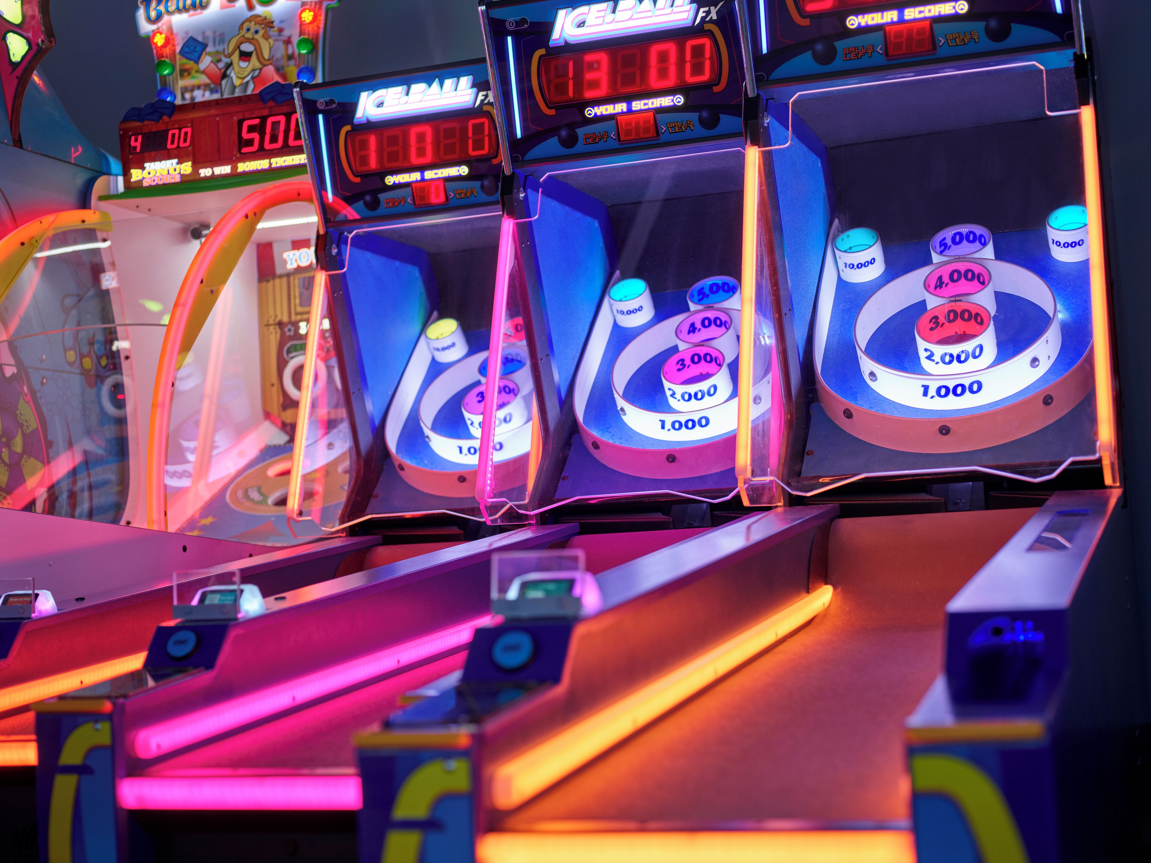 A row of arcade machines with digital score displays and prize wheels.